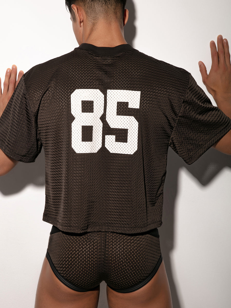Person wearing a black sports jersey with the number 85 on the back against a white background