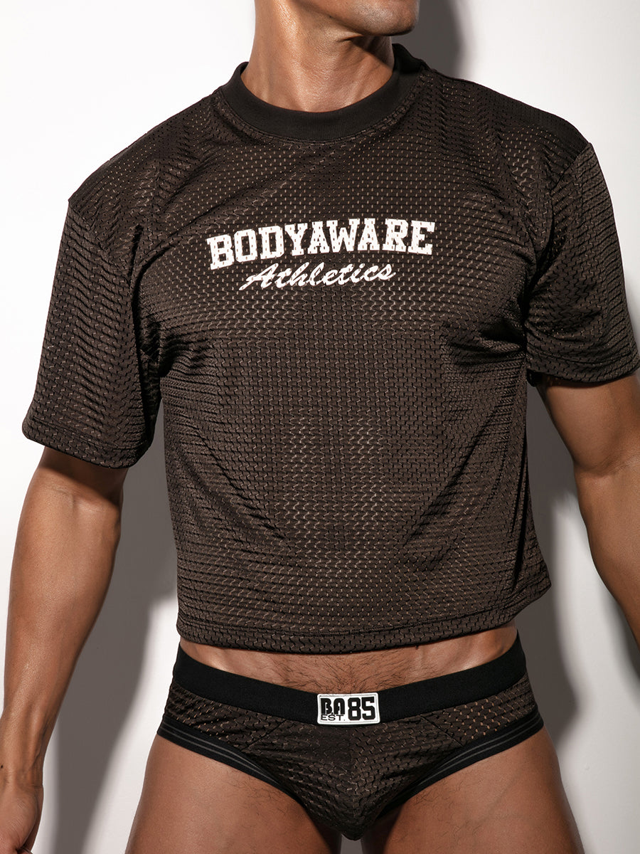 A man wearing a black mesh athletic jersey with matching underwear briefs.