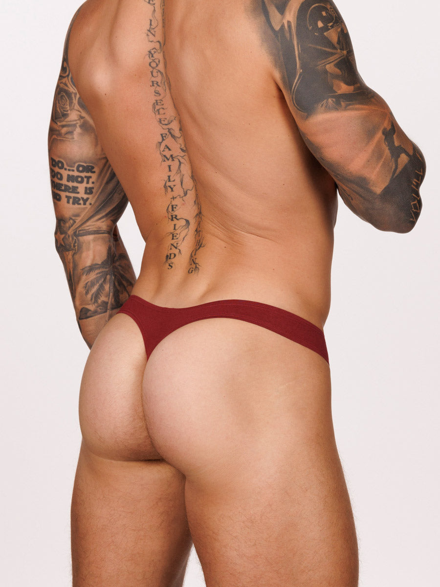 Back view of a male model wearing a burgundy red Body Aware thong