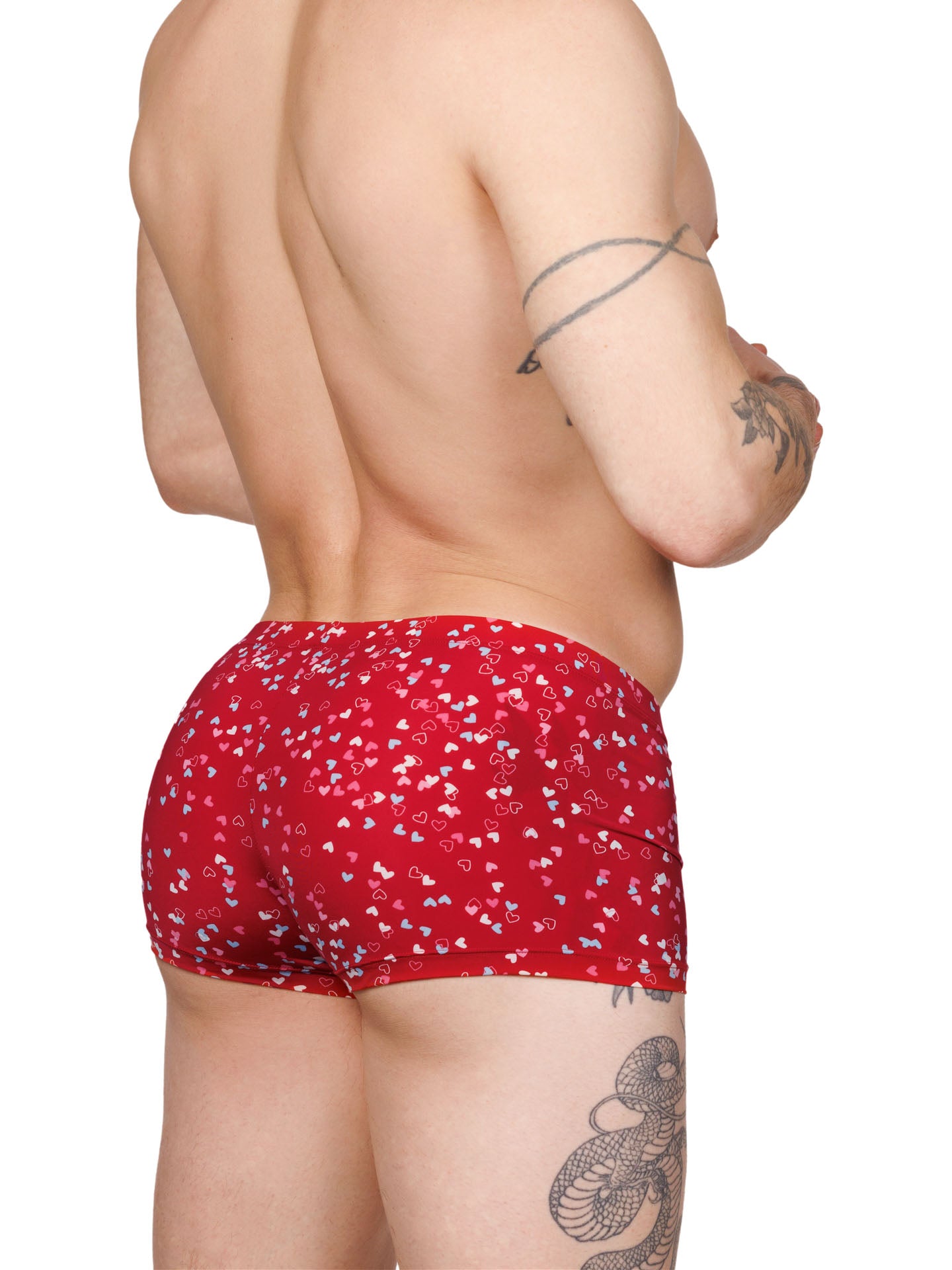 Side view of a male model wearing red Body Aware boxer shorts with a multicolor heart pattern