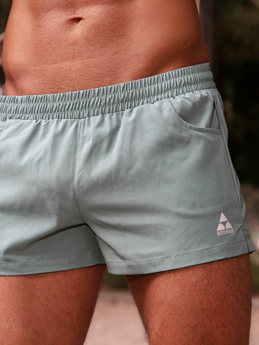 Closeup view of green athletic shorts with a white Body Aware logo