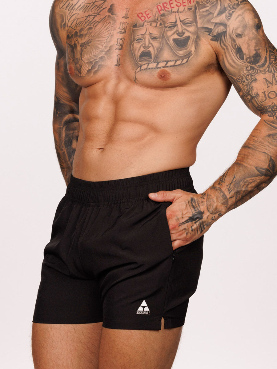 Side view of a male model wearing black Body Aware athletic shorts with pocket