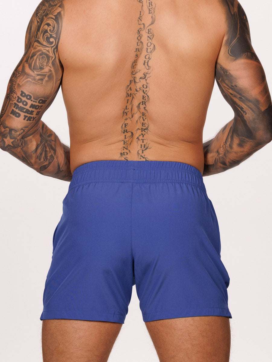 Back view of a male model wearing blue Body Aware athletic shorts