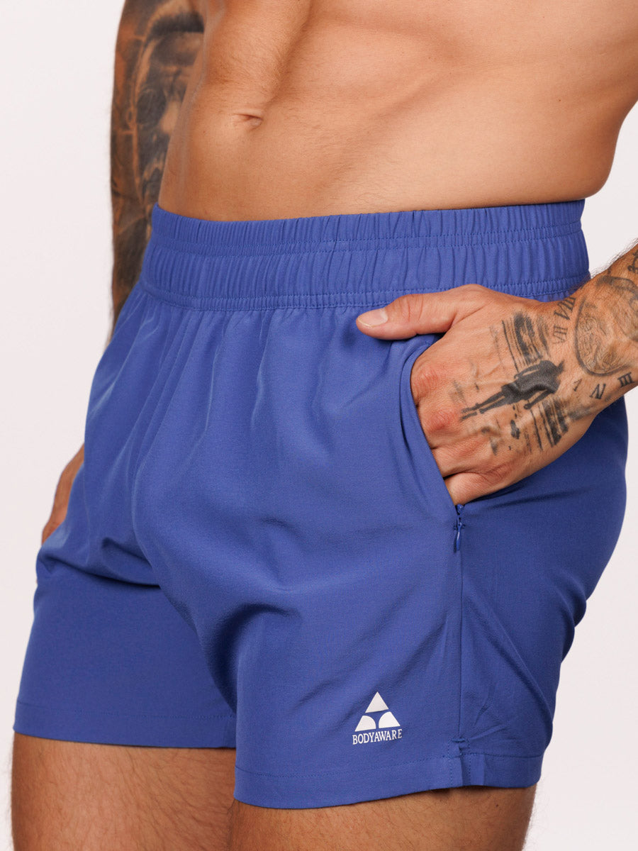 Closeup view of a male model wearing blue Body Aware athletic shorts