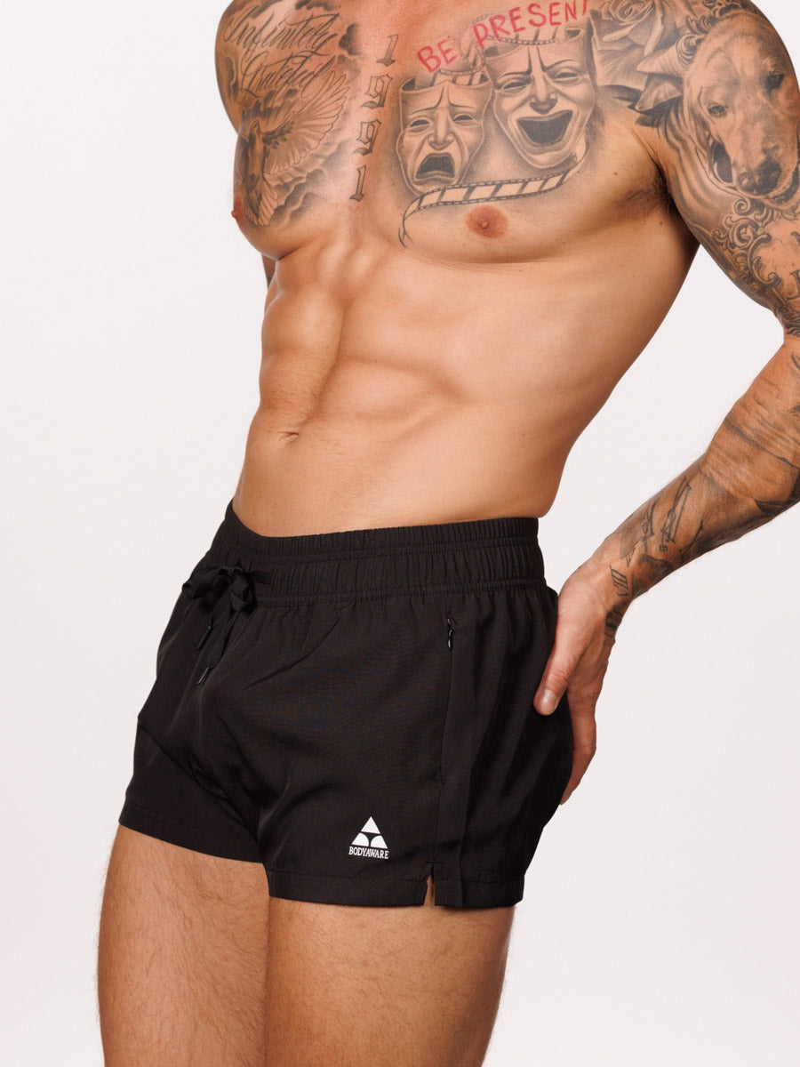 Side view of a male model wearing black Body Aware gym shorts with drawstring