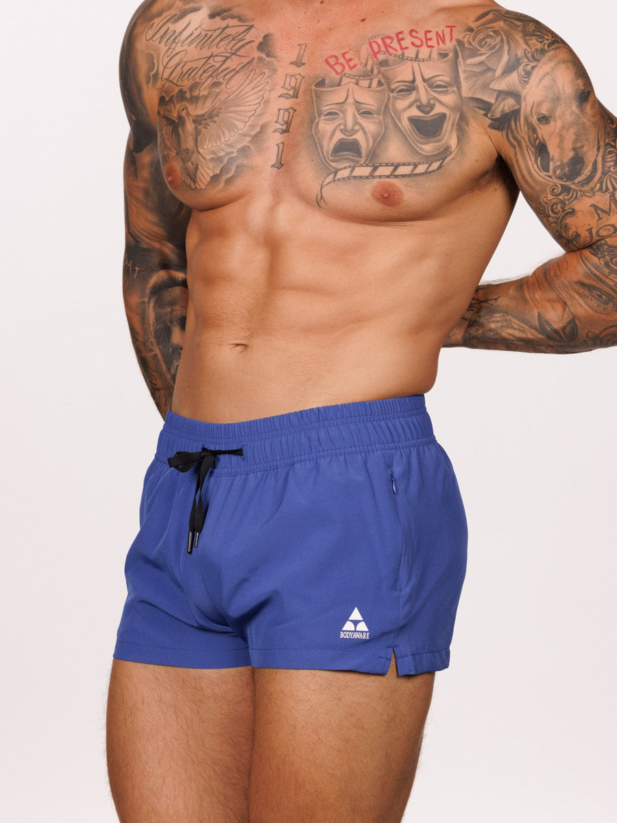 Side view of a male model wearing blue Body Aware square leg gym shorts 