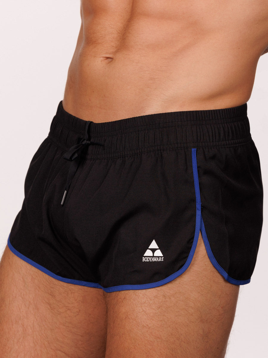 Closeup view of a male model wearing black Body Aware running shorts