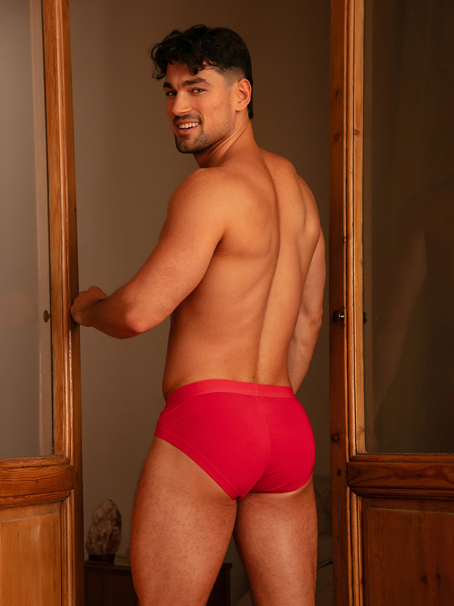 Rear view of a man wearing red Body Aware briefs standing in a doorway.