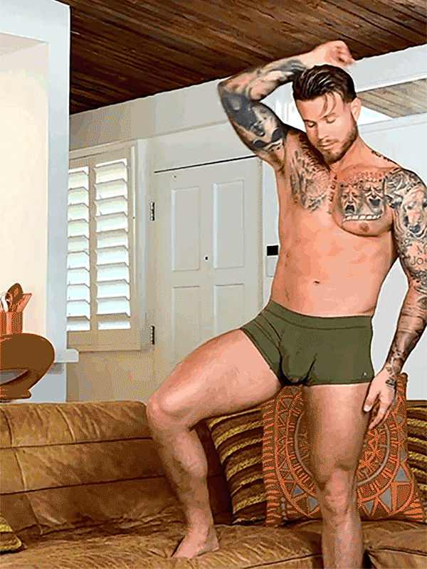 gif of a man spinning wearing an olive green body aware glow boxer in a home