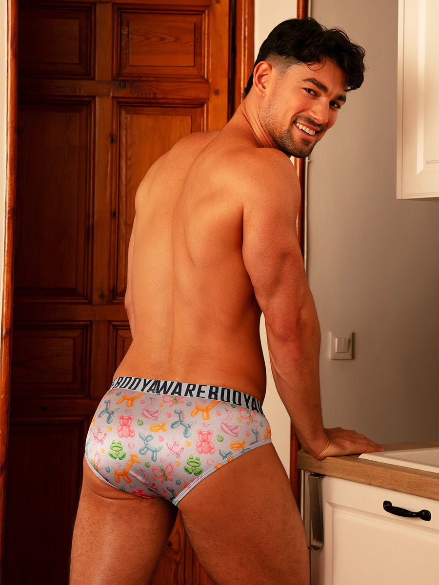 Back view of a man wearing light blue satin briefs with a Body Aware branded waistband.