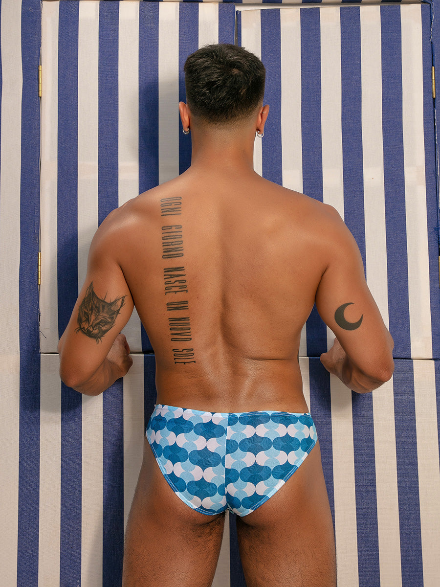 Rear view of a male model posing wearing a pair of blue and white wave pattern men's briefs