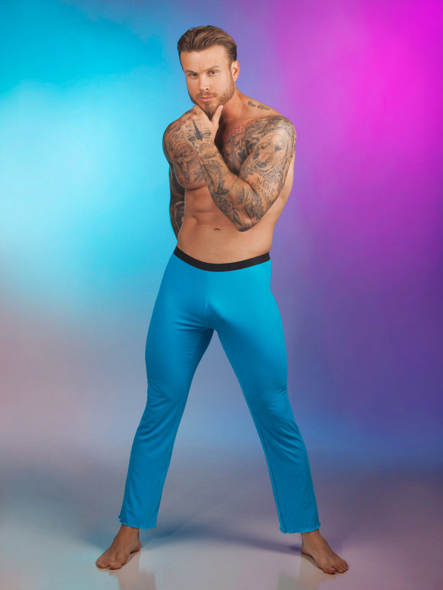 A male model wearing turquoise Body Aware lounge pants against a pink and blue background