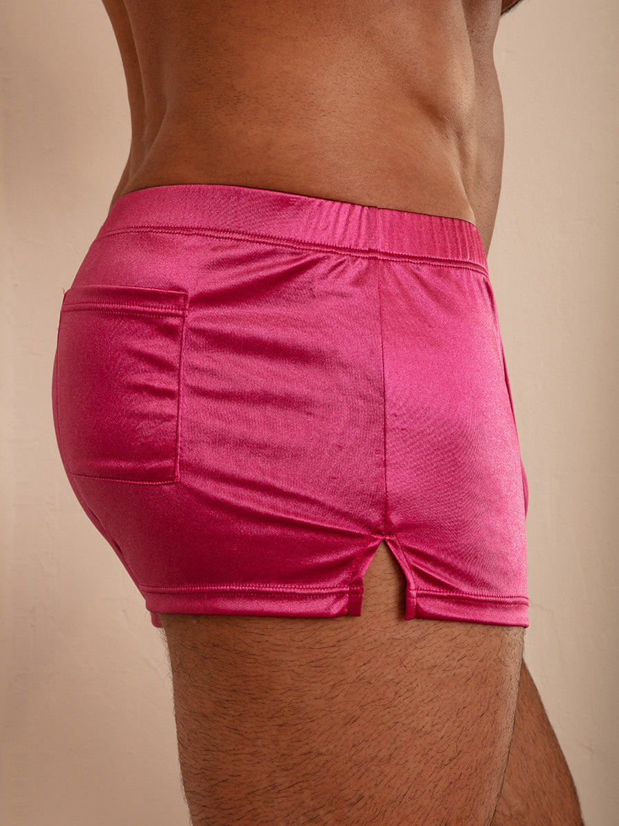 A close-up side view of a person wearing pink satin shorts.