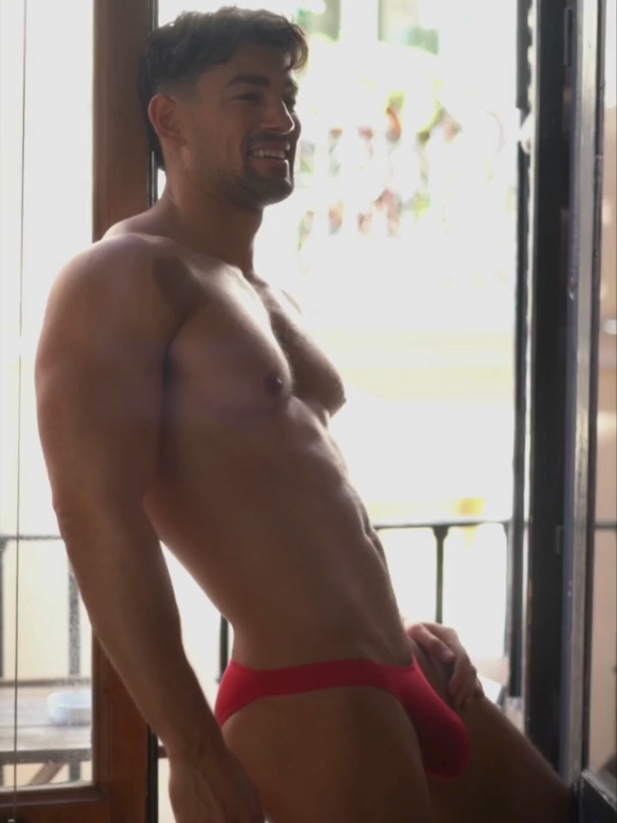Video of a man wearing a red Body Aware bikini brief, standing in a doorway.
