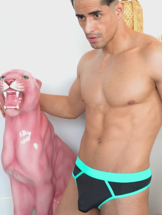 Video of a man modeling black thong underwear with blue trim.