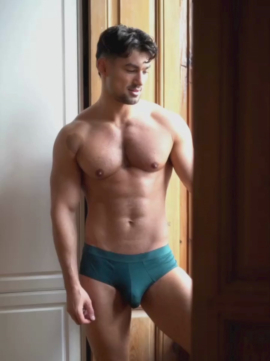Video of a man wearing teal green Body Aware briefs, standing in a doorway.